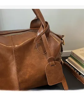 Close-up of brown faux leather bag showing fine texture, stitching, and metal zipper detail