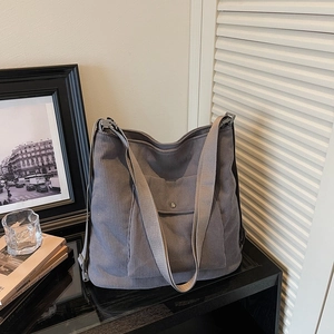 Detail of grey corduroy tote bag showing front pocket with magnetic metal buckle