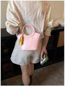 Pink glossy patent leather bucket bag with rainbow beaded charm and top handle