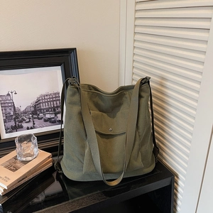 Detail of army green corduroy tote bag with wide strap and buttoned front pocket