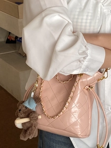 Sac seau matelassé rose avec bandoulière chaîne et breloque ours porté par un mannequin