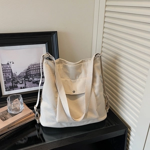 Detail view of a beige corduroy tote bag featuring a front pocket and soft texture