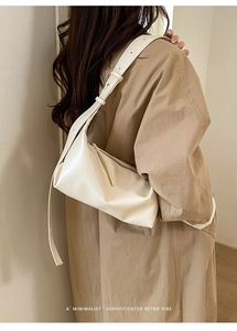 Close-up of cream white minimalist baguette bag featuring a wide adjustable shoulder strap
