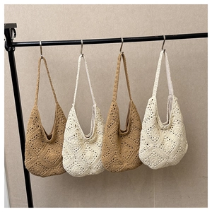 Detail view of handmade crochet tote bags in khaki and beige hanging on a black display rack