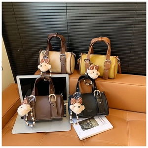 Detail view of four vintage mini bowling bags in beige, yellow, brown, and black with charms