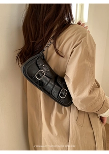Dettaglio borsa sottobraccio nera vintage con fibbie argentate indossata dalla modella