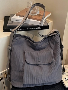 Minimalist grey corduroy tote bag with front pocket shown on a white shelf
