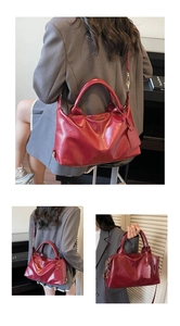 Deep red leather Boston bag showing multi-way wear with top handles and long strap