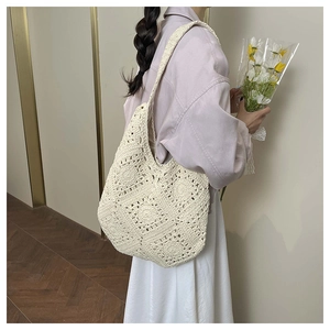 Close-up of beige crochet tote bag featuring hollow floral pattern and woven strap