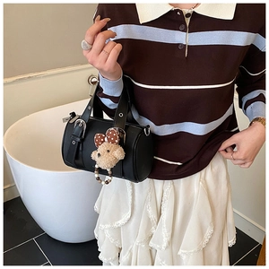 Close-up of black leather bowling bag with cute plush bear pendant and metal eyelets