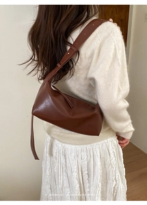 Detail of dark brown leather crossbody bag featuring adjustable strap on model