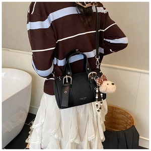 Detail view of black vintage bowling bag with puppy charm and silver buckle straps