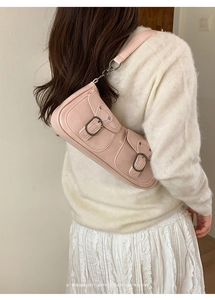 Dettaglio della borsa sottobraccio in pelle rosa con doppie fibbie e tracolla a catena