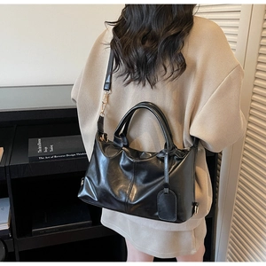 Detail view of the black faux leather tote bag showing texture and stitching on a model
