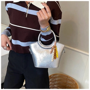 Detail of silver metallic textured bucket bag with decorative colorful bead charm