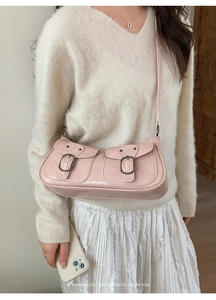 Dettaglio di una mini borsa in ecopelle rosa lucida con fibbie in bronzo vintage