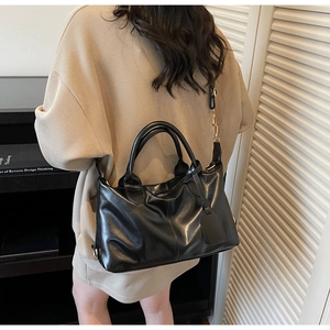 Detailed view of black leather tote bag with gold hardware and adjustable strap