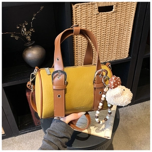Detailed macro of yellow leather bowling bag with contrast brown trim and sheep charm