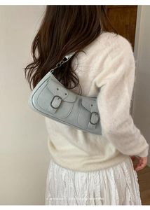 Vista posteriore di una modella con borsa a tracolla retrò azzurra con doppie fibbie