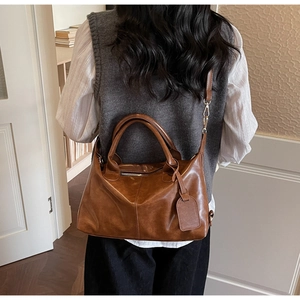 Brown vintage leather handbag with adjustable crossbody strap shown on a model