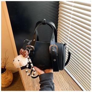 Detail of black bowling bag with silver metal buckles and cute plush doll pendant