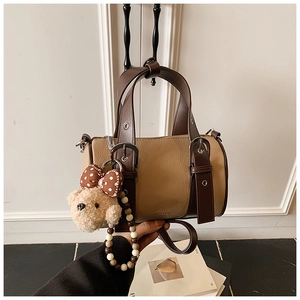 Detail of retro khaki bowling bag with brown handles and a cute plush bear charm