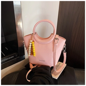 Pink bucket bag with lychee texture featuring round handle and beaded charm detail