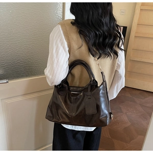 Detail view of deep brown oily wax leather tote bag worn as a shoulder bag on a model
