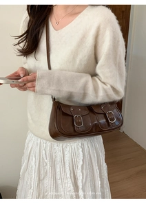 Dettaglio di una borsa a tracolla retrò marrone scuro con due tasche frontali e fibbie in metallo