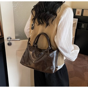 Deep brown large capacity faux leather bag shown on shoulder in a cozy interior