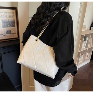 Détail d'un sac à bandoulière en cuir blanc matelassé avec une chaîne dorée sur mannequin