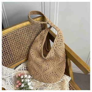 Close-up of a handmade woven straw tote bag with intricate cutout patterns for summer