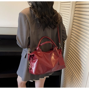 Detail of burgundy large capacity tote bag with gold hardware shown on a model