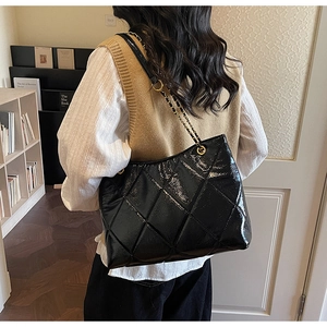 Détail du sac cabas en cuir verni noir brillant avec coutures matelassées élégantes