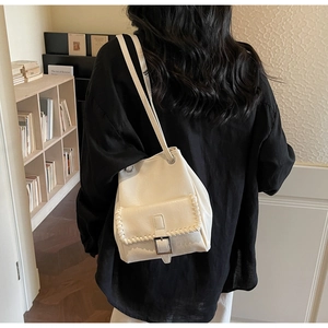 Detail of cream white bucket bag with woven edge and silver metal buckle on a shoulder strap