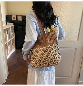 Detail of a large woven tote bag in contrast colors with leather straps and tassels