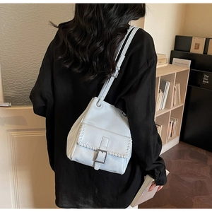 Detail of light blue leather shoulder bag featuring white braided stitching and metal buckle