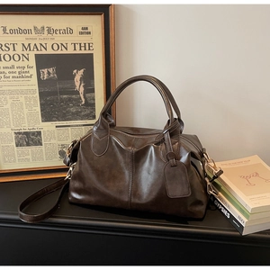 Detail of dark brown boston bag in vintage polished leather on a retro desk setup