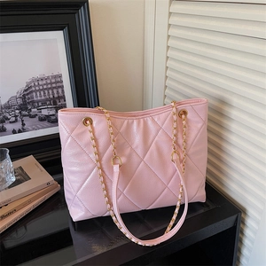 Détail d'un sac cabas rose brillant avec bandoulière en chaîne dorée et motif matelassé