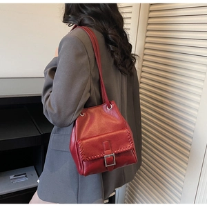 Detail of red leather bucket bag with whipstitch trim and silver buckle on shoulder