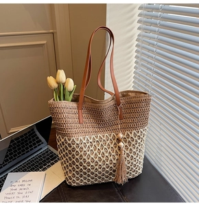 Detail of woven tote bag featuring mixed textures, brown leather handles and a tassel