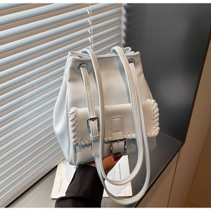 Detail of light blue bucket bag with woven trim, silver buckle, and drawstring closure