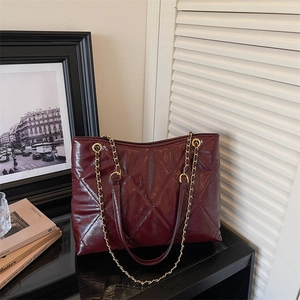 Détail du sac fourre-tout bordeaux matelassé avec fini brillant et bandoulière chaîne dorée