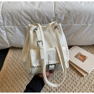 Detail of white bucket bag with woven stitching edges and silver metal buckle