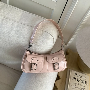 Dettaglio della borsa a tracolla in pelle rosa con fibbie decorative su un divano bianco