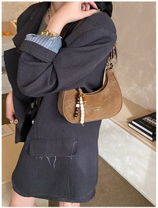 Detail of a brown suede hobo bag featuring vintage saddle shape and beaded zipper charm