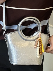 Silver metallic leather bucket bag with unique round handle and colorful beaded tassel charm