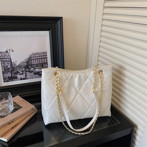 Détail du sac cabas blanc matelassé avec une élégante bandoulière en chaîne dorée