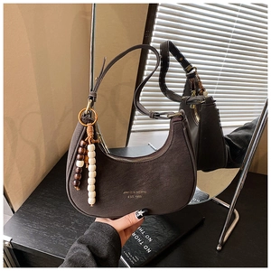 Detail of vintage brown hobo bag featuring beaded fringe and logo on soft suede leather