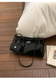 Dettaglio borsa a spalla nera lucida con fibbia argentata e mini portamonete incluso
